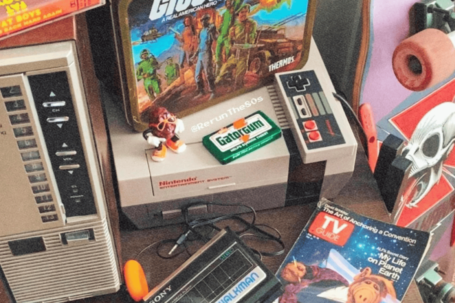 1980s memorabilia, including a metal GI Joe lunchbox, an issue of TV Guide with Alf on the cover, the Nintendo Entertainment System (NES), and a Sony Walkman