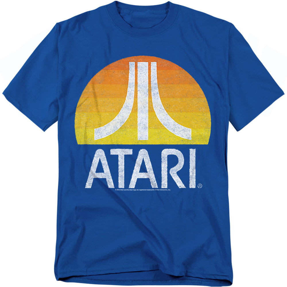 Blue t-shirt featuring the Atari logo in white over a retro sunset gradient circle of orange and yellow, with a distressed vintage effect.