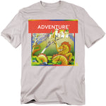 A light gray t-shirt featuring the classic Atari Adventure box art. The design shows a medieval knight confronting a dragon in front of a castle, framed by a bold red banner with the word “ADVENTURE” in white text.