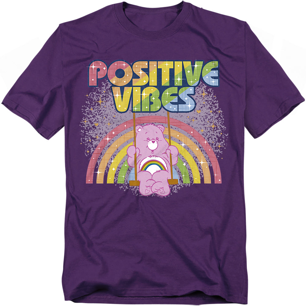 Purple Care Bears t-shirt with Cheer Bear swinging in front of a rainbow and the words “Positive Vibes.”