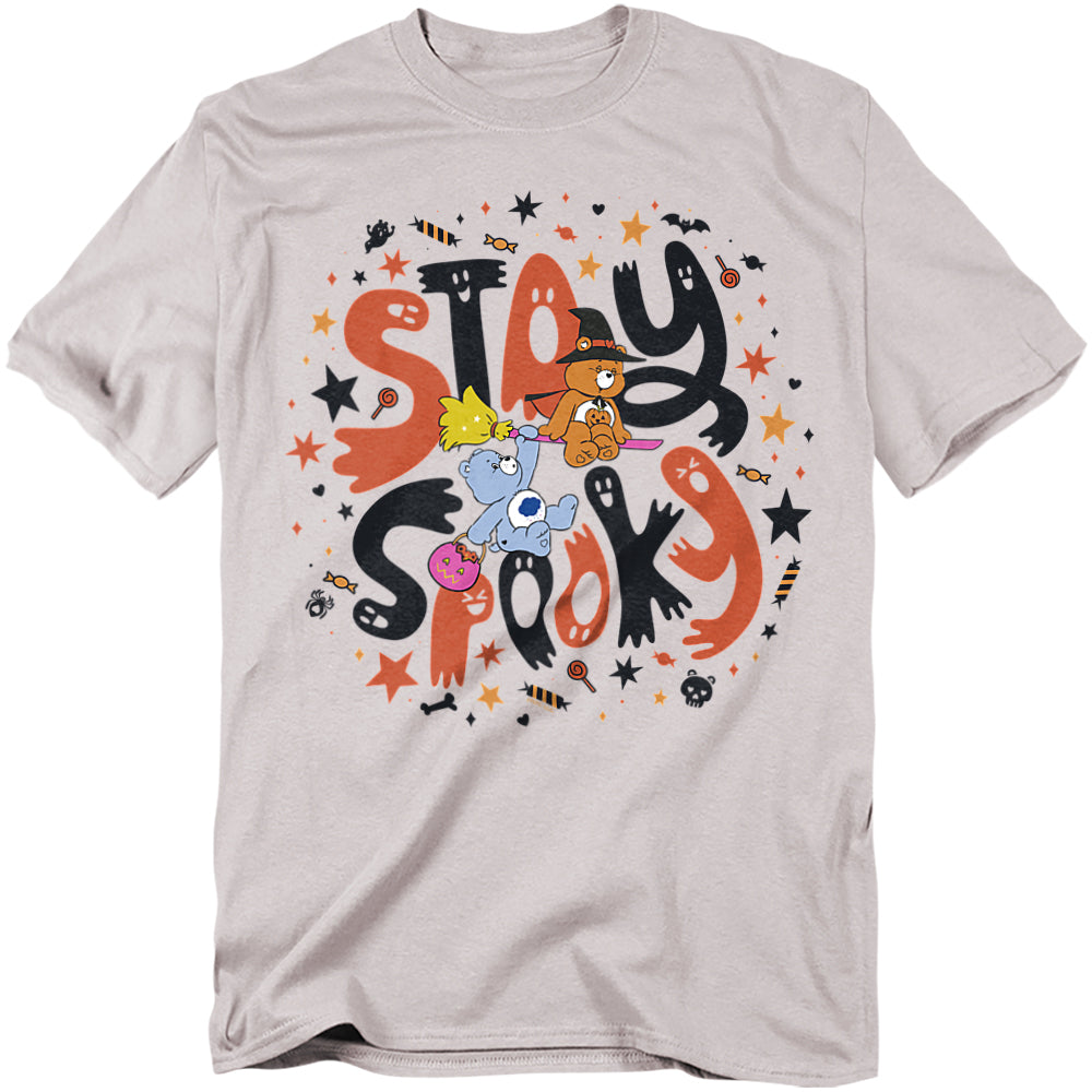 Light gray t-shirt with colorful Halloween design featuring Tenderheart Bear in a witch hat on a broom, Grumpy Bear holding candy, and Funshine Bear, surrounded by stars, bats, candy, and ghosts with bold lettering that reads “Stay Spooky.”