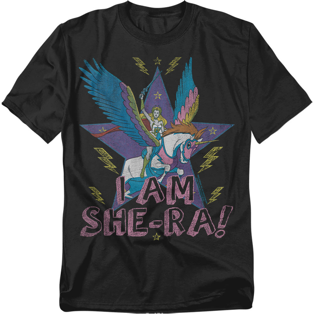 A black t-shirt featuring She-Ra riding her winged unicorn Swift Wind. Behind them is a large purple star with lightning bolts and yellow stars. Distressed pink lettering at the bottom reads “I AM SHE-RA!”