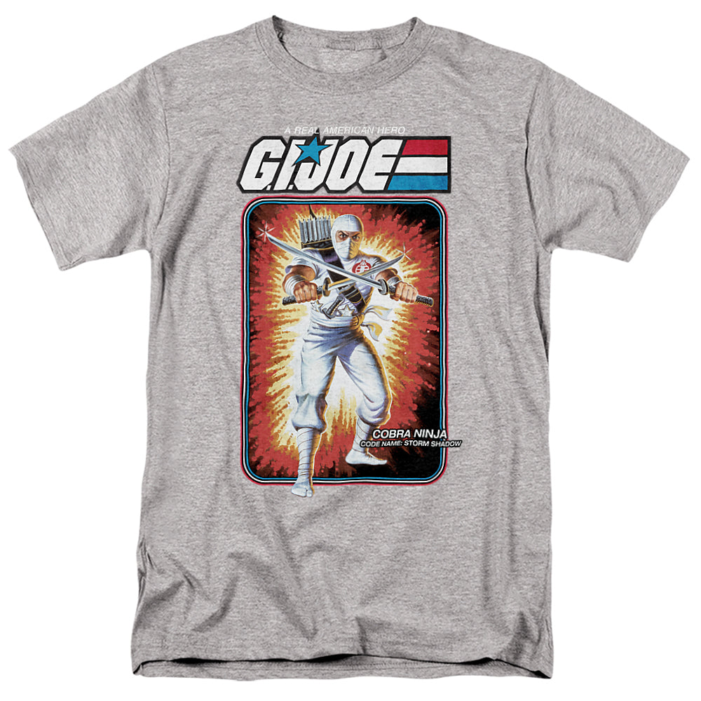 Heather gray t-shirt featuring G.I. Joe’s Storm Shadow in his classic white ninja outfit with swords, against explosive vintage card art background.