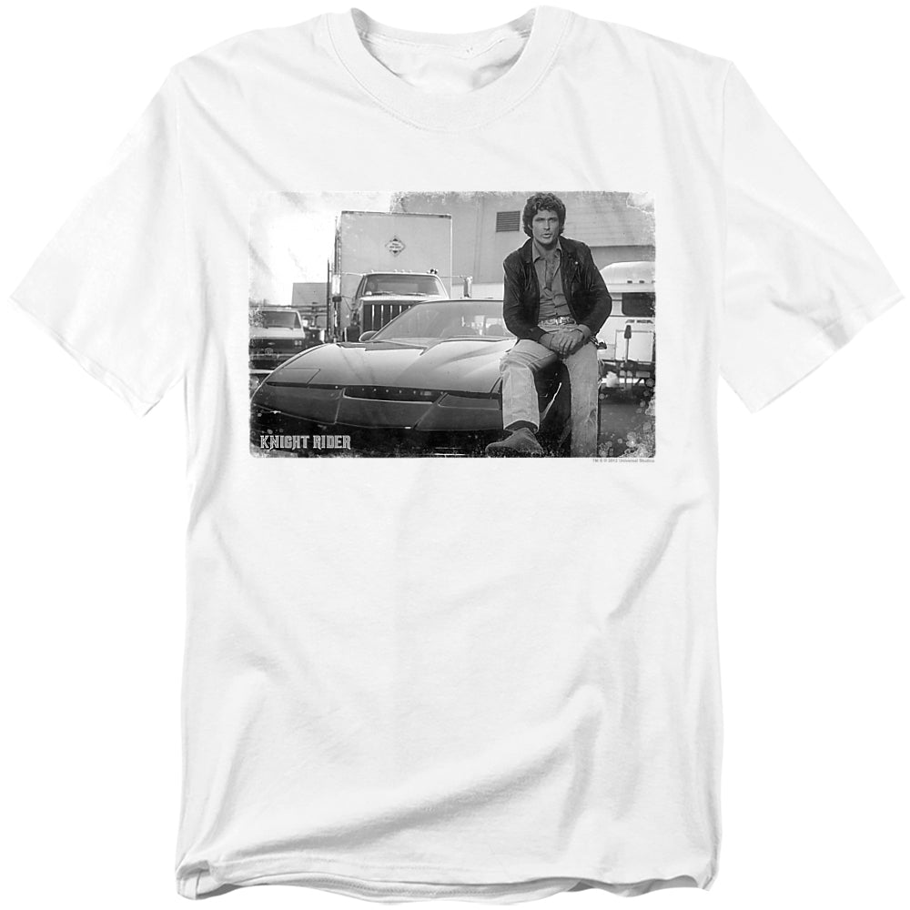 White t-shirt featuring a black-and-white photo of Michael Knight (David Hasselhoff) leaning against KITT, the iconic Pontiac Trans Am from Knight Rider. The Knight Rider logo appears in the bottom corner.