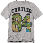Teenage Mutant Ninja Turtles 1984 gray t-shirt featuring Leonardo, Donatello, Michelangelo, and Raphael inside varsity-style '84' numbers.