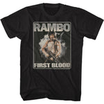 Black vintage-style t-shirt featuring the classic Rambo: First Blood movie poster art, with John Rambo holding a machine gun and standing against a smoky, action-filled backdrop.
