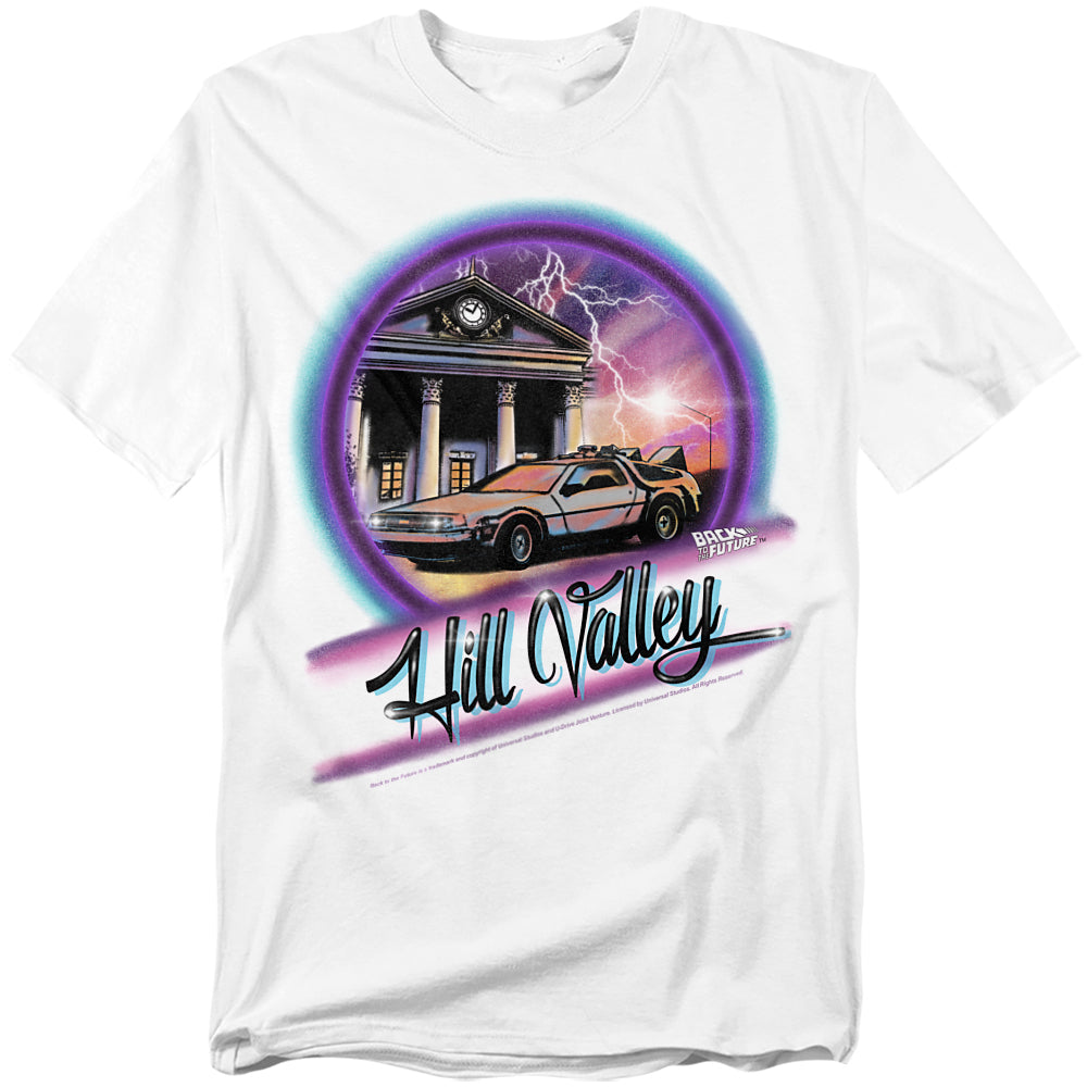 White t-shirt with Back to the Future graphic showing the DeLorean in front of Hill Valley’s clock tower with lightning and neon airbrush design.