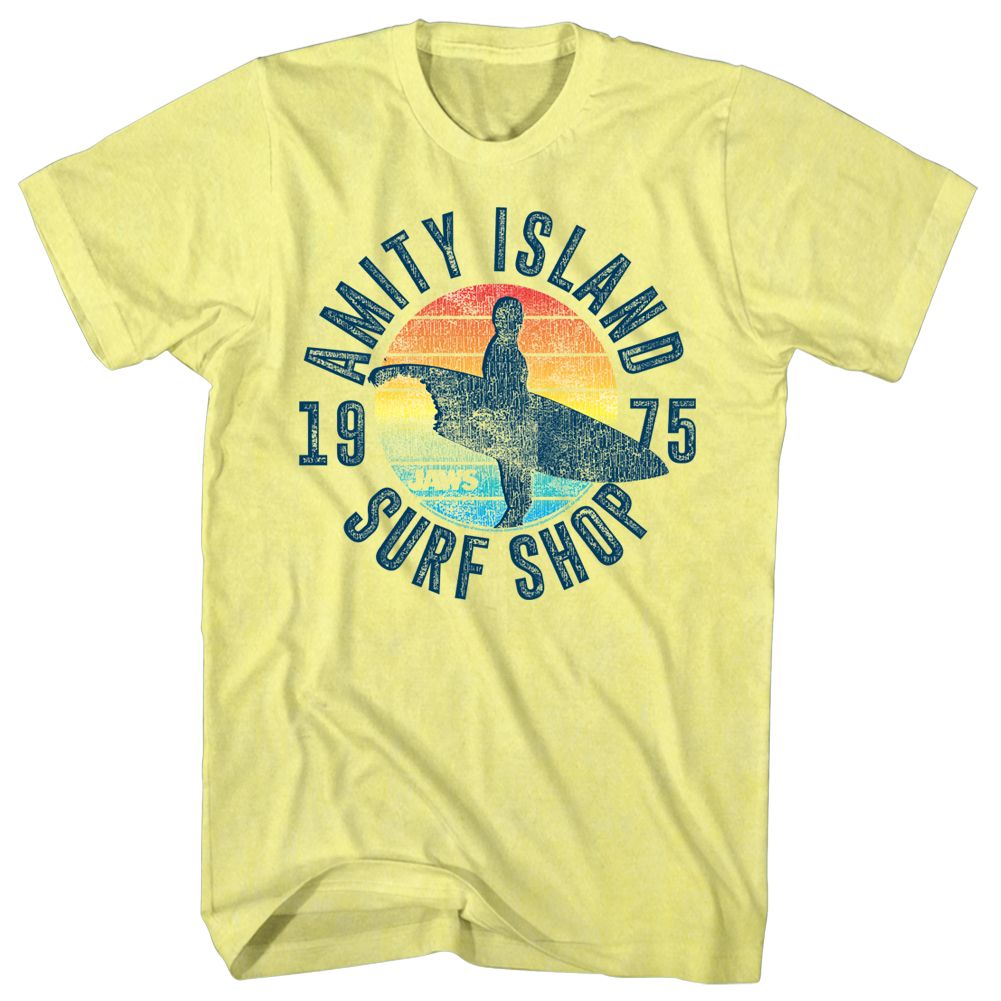Pale yellow Jaws T-Shirt featuring a surfer silhouette, retro sunset artwork, and Amity Island Surf Shop 1975 graphic