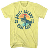 Pale yellow Jaws T-Shirt featuring a surfer silhouette, retro sunset artwork, and Amity Island Surf Shop 1975 graphic