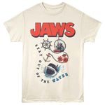 Cream-colored Jaws T-Shirt featuring the JAWS logo, shark graphic, Orca boat, anchor, ship wheel, flowers, and “Stay Out of the Water” text
