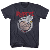 Heather navy T-shirt featuring a vintage-style illustration of Popeye inside a circular frame with a speech bubble saying “I y’am what I y’am” and bold red “POPEYE” text above.
