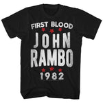 Black Rambo T-shirt with bold white lettering reading “First Blood John Rambo 1982” and red stars, celebrating the 1982 action film classic.