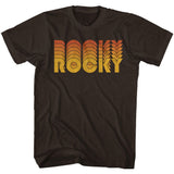 Brown T-shirt with a retro-style orange and yellow “Rocky” logo inspired by the 1976 boxing movie.