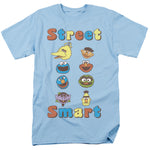 Light blue Sesame Street Smart T-shirt featuring a grid of classic character faces with colorful “Street Smart” lettering